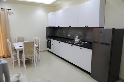 a kitchen with white cabinets and a black refrigerator at Vila Emi in Durrës