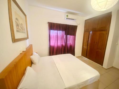 a bedroom with a white bed and a window at DAMAS in Douala