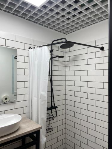 uma casa de banho com uma cortina de chuveiro e um lavatório em Apartment Loftas13-6 em Kretinga