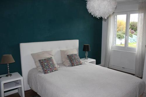 une chambre avec un lit blanc et un mur vert dans l'établissement L’Augustine, maison contemporaine à la campagne !, au Tilleul