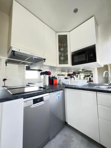 a kitchen with white cabinets and white appliances at Apartment HOME in Paris with View, 15min to center in Paris