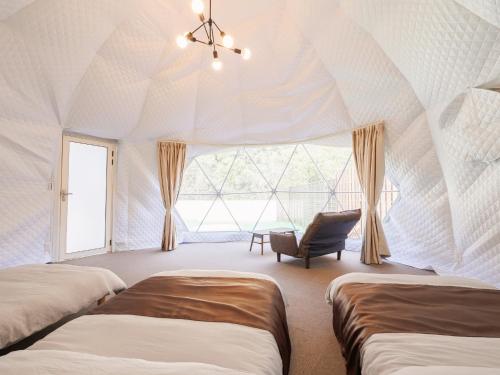 廣島的住宿－Riverside Glamping Kamiseno - Vacation STAY 92770v，帐篷内的房间,配有两张床和一把椅子