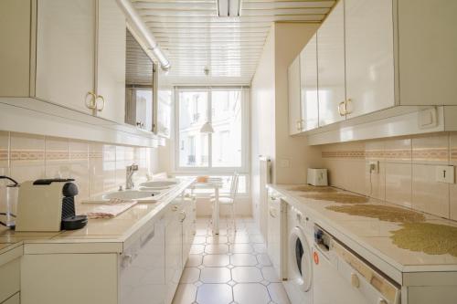 - une cuisine blanche avec un évier et un lave-vaisselle dans l'établissement Appartement Tour Eiffel & Trocadéro, à Paris
