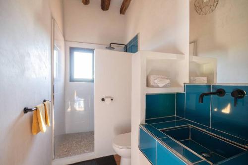 a bathroom with a blue sink and a toilet at Radiant 5 BR family home with jacuzzi + roof deck in Palau de Santa Eulalia