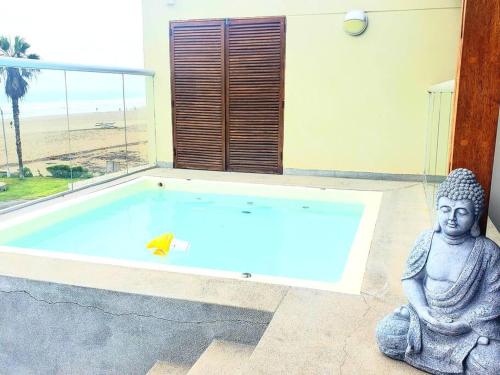 une statue d'un buddha assis à côté d'une piscine dans l'établissement Bujama vista al mar, à Asia