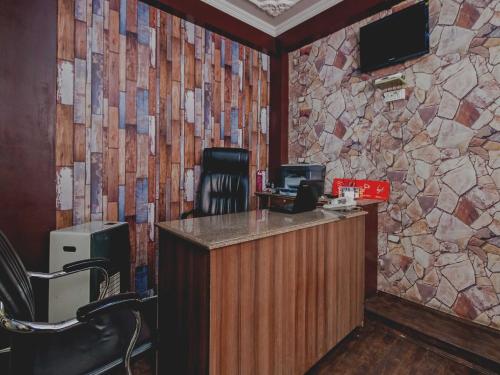 City Star Hotel & Restaurant في Jawāharnagar: مكتب مع كرسي وجدار حجري
