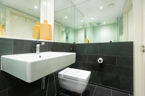 ein Badezimmer mit einem Waschbecken, einem WC und einem Spiegel in der Unterkunft Gorgeous Central 2BR Flat, Belgravia, Chelsea in London