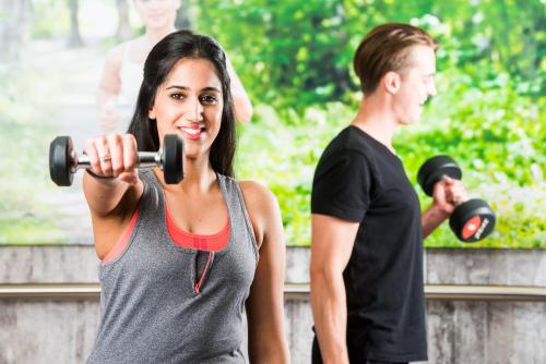 a man and a woman exercising with weights at Ramada Encore Leicester City Centre in Leicester