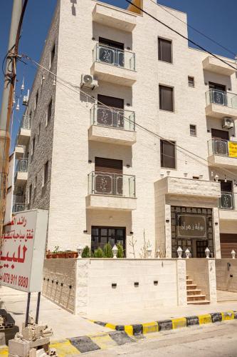 a tall white building with balconies on a street at Prestige hotel apartment in Amman