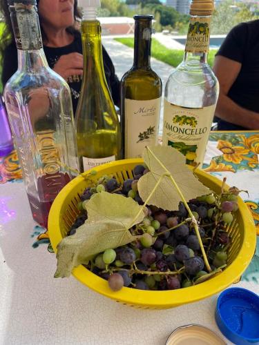 a yellow bowl of grapes on a table with bottles of wine at Villa Smeralda - Luxury on the Italian Riviera in Lavagna