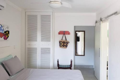 a white bedroom with a bed and a chair at Apartamento Sorocotuba Guaruja in Guarujá