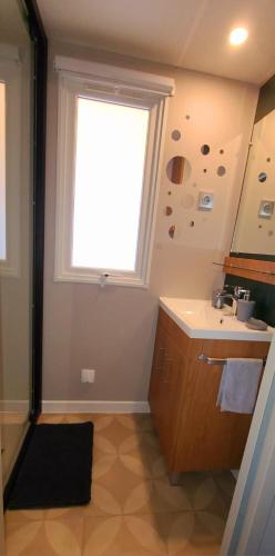 a bathroom with a sink and a window at Mobil-home Le cocon FUN PASS NON INCLUS in Canet-en-Roussillon