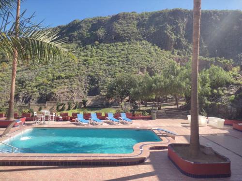 una piscina con tumbonas y una montaña en Casa de campo con piscina en Las Palmas de Gran Canaria