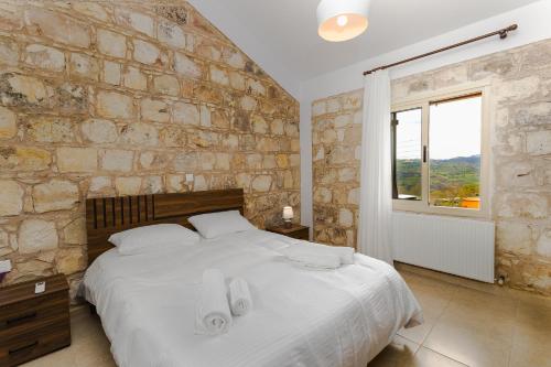 a bedroom with a large bed and a stone wall at Simou villa in Paphos City