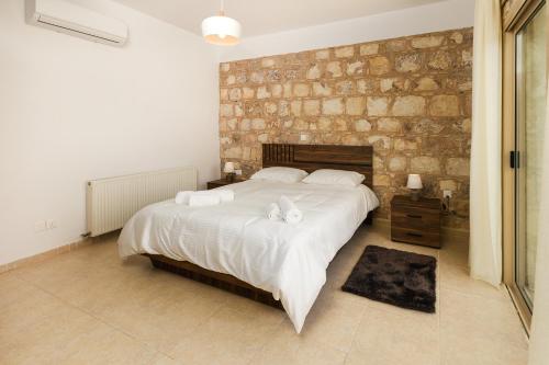 a bedroom with a large bed and a stone wall at Simou villa in Paphos City