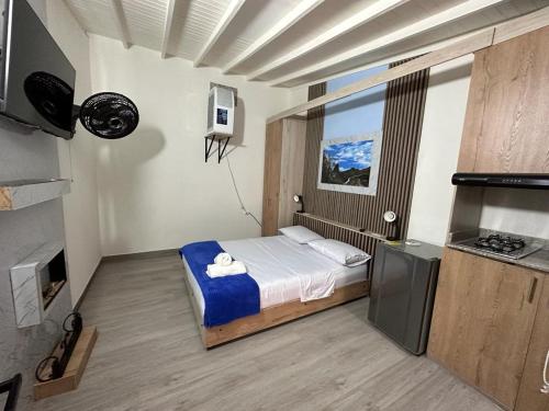 una piccola camera con letto e televisore di Hotel Lares 70 Laureles a Medellín