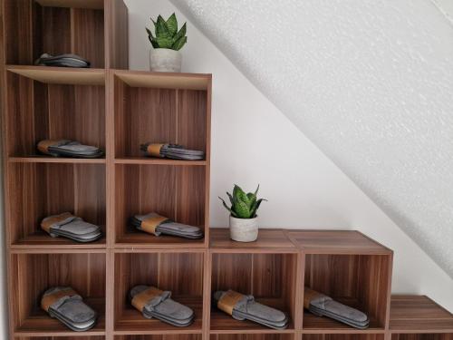 a wooden book shelf with two plants on it at Modern And Spacious 3 Bedroom Family House with Workspace in Colchester