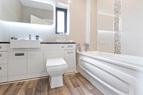 a white bathroom with a tub and a toilet and a sink at Modern One Bedroom Flat in Morden SM4, London in Morden
