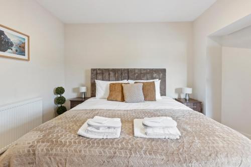 a bedroom with a large bed with towels on it at Modern One Bedroom Flat in Morden SM4, London in Morden
