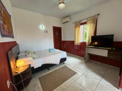 een slaapkamer met een bed en een flatscreen-tv bij Pousada Villa Flamboyant in Beberibe