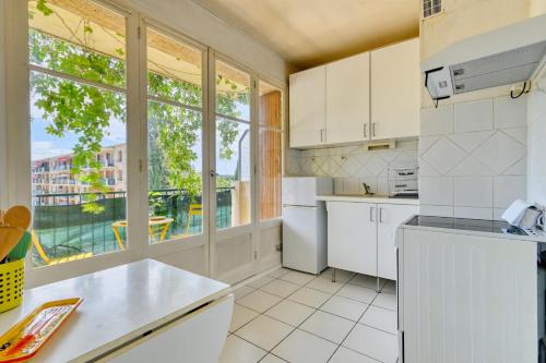 Il comprend une cuisine équipée d'appareils électroménagers blancs et une grande fenêtre. dans l'établissement Charming apartment with balcony and panoramic view, à Aix-en-Provence