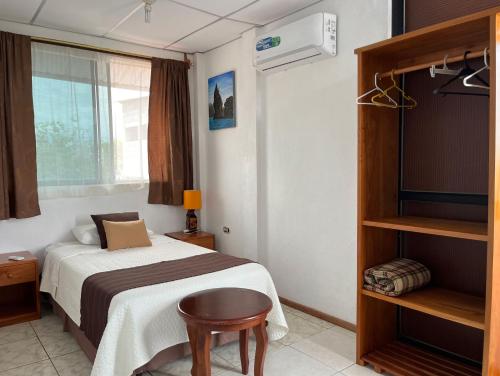 een slaapkamer met een bed, een stoel en een raam bij Maytenus Galapagos in Puerto Ayora