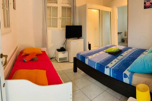 a bedroom with two twin beds and a television at Maison de 7 chambres avec piscine privee terrasse et wifi a Sainte Anne in Sainte-Anne