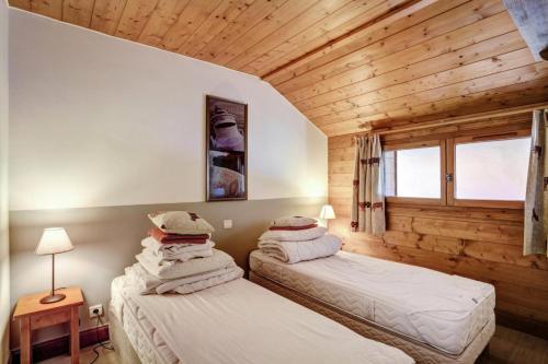 - 2 lits dans une chambre avec un mur en bois dans l'établissement Résidence Les Hauts Bois - maeva Home - Appartement 4 pièces 8 personnes Sélection MAE-9753, à Aime La Plagne
