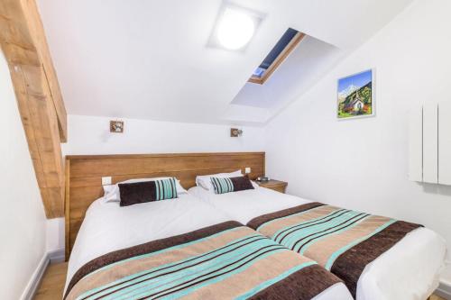 2 łóżka w sypialni z białymi ścianami w obiekcie Résidence Les terrasses d'Eos - maeva Home - 3 Pièces 6 Personnes - Sélect 67 w mieście Flaine
