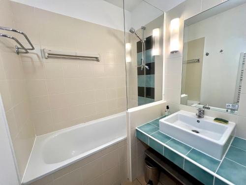 a bathroom with a sink and a tub and a mirror at DANS LES BRAS DE NEPTUNE - Plage de TRESTRAOU - Piscine - 4 à 5 personnes in Perros-Guirec