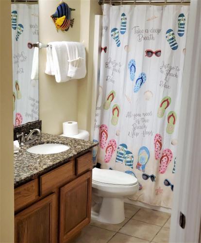 a bathroom with a shower curtain with a toilet and a sink at Legacy Tower II 602 in Gulfport