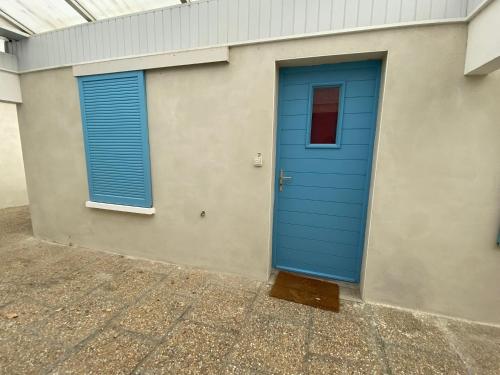 une porte bleue et deux fenêtres sur un bâtiment dans l'établissement Studio en bord de mer, tous commerces animations, à Saint-Hilaire-de-Riez