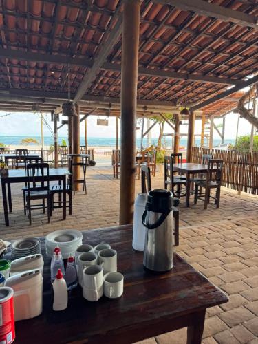 a wooden table with cups on it with a beach in the background at Pousada das Canoas in Acaraú