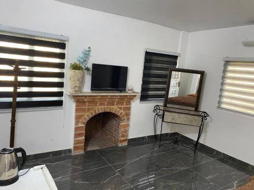 um quarto com lareira, televisão e espelho em huseein rooms em Gérasa