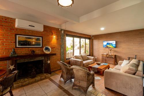 a living room with a couch and a fireplace at Pousada Descanso do Rei - Vista Para o Mar & Melhor Localização da Praia do Rosa in Praia do Rosa