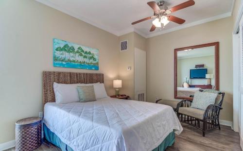 a bedroom with a bed with a ceiling fan and a mirror at Ocean Club 704 in Biloxi