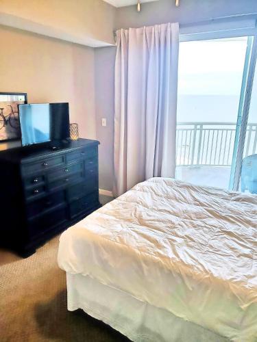 Un dormitorio con una cama y un televisor y una ventana. en Legacy Tower Two 904, en Gulfport