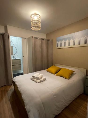 a bedroom with a large white bed with yellow pillows at Le Graverend T2 Charmant et central in Rennes