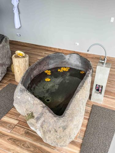 a stone bath tub with flowers in it on a wooden floor at Vibra Healing Lodge y Spa in Teniente Hugo Ortiz