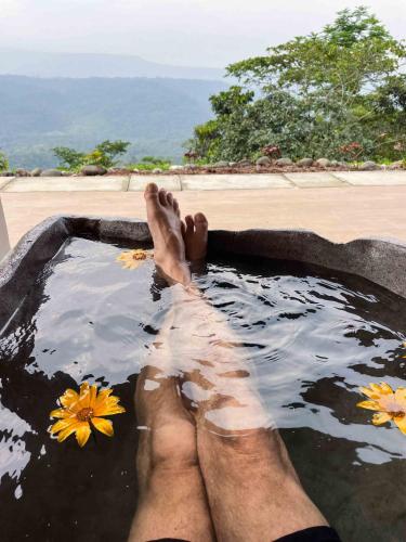 a man laying in a bath tub with his feet in it at Vibra Healing Lodge y Spa in Teniente Hugo Ortiz