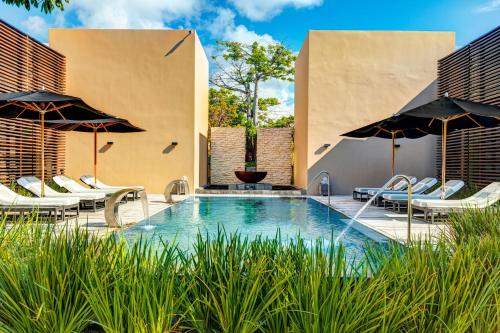 an outdoor swimming pool with chairs and umbrellas at NIZUC Resort & Spa in Cancún