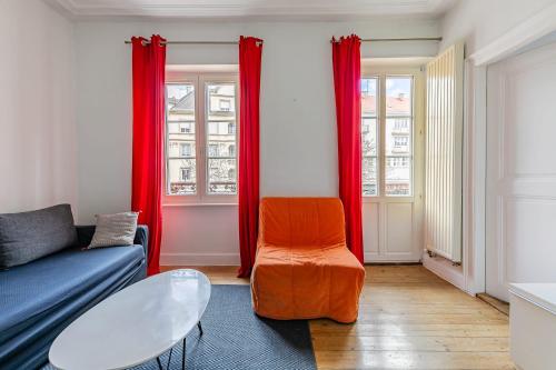 a living room with a blue couch and red curtains at Appartement 2 chambres avec garage à strasbourg in Strasbourg