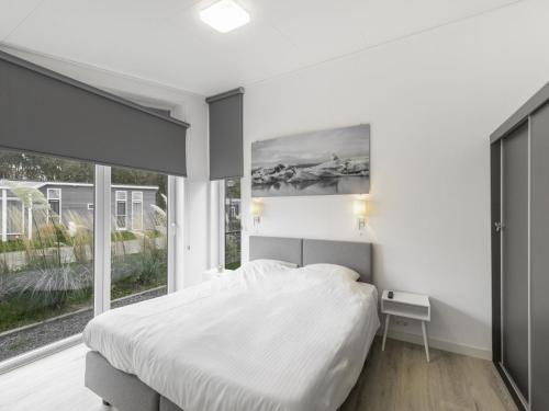 een slaapkamer met een bed en een groot raam bij Modern chalet with jetty and terrace in Wemeldinge