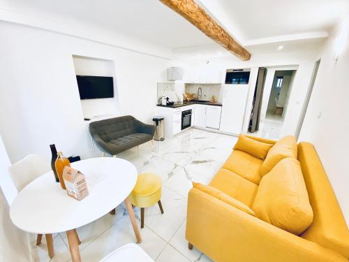 ein Wohnzimmer mit einem gelben Sofa und einem Tisch in der Unterkunft T3 carré d’or plein centre in Nizza