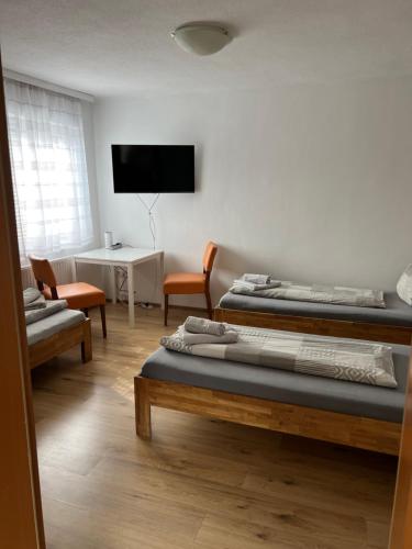 a room with two beds and a tv on the wall at Roccos Raum in Kapfenberg