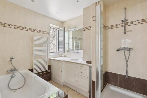 uma casa de banho com uma banheira, um lavatório e um chuveiro em Appartement Boulogne-Billancourt nord Roland Garros em Boulogne-Billancourt
