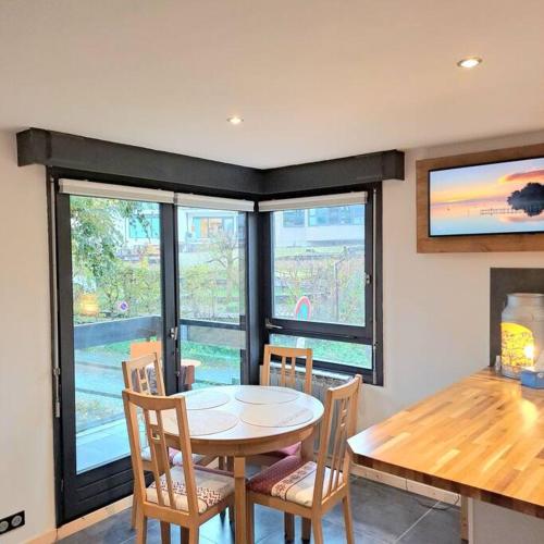 une salle à manger avec une table, des chaises et des fenêtres dans l'établissement Casa Peghera, Chamonix (hypercentre), à Chamonix-Mont-Blanc