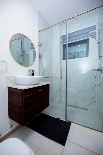 a bathroom with a glass shower and a sink at Park Apartments in Accra