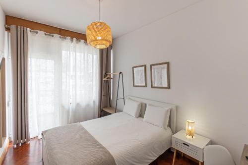 a white bedroom with a white bed and a window at Lolla's City House 2 in Porto