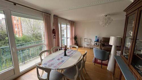 une salle à manger avec une table et des chaises et une fenêtre dans l'établissement Appartement Boulogne-Billancourt nord Roland Garros, à Boulogne-Billancourt